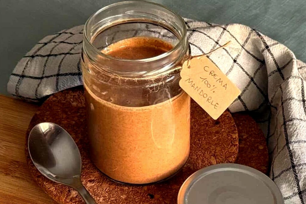 Crema di mandorle fatta in casa in barattolo di vetro con etichetta in cartoncino e scritta a mano