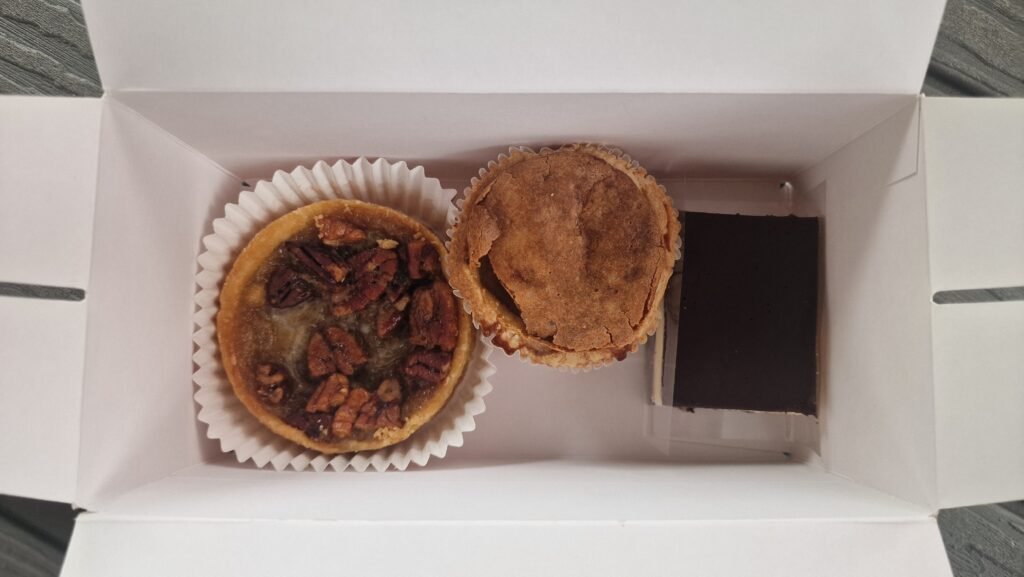 Tre dolci in una box d'asporto: pecan tart, butter tart, nanaimo bar