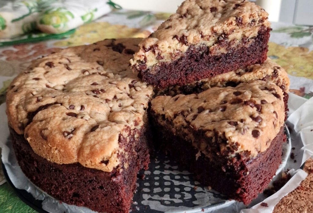 Torta brookie con uno spicchio tagliato e appoggiato sul resto della torta